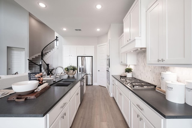 kitchen featuring light hardwood / wood-style floors, stainless steel appliances, sink, white cabinetry, and backsplash