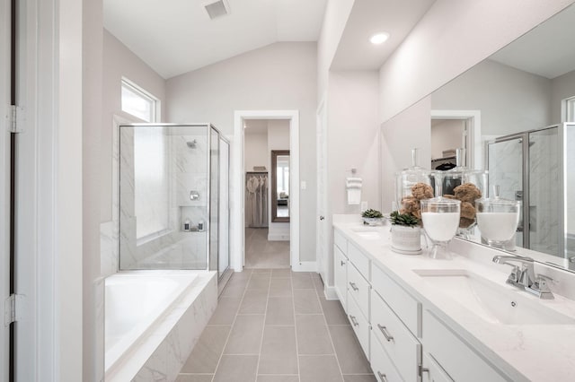 bathroom featuring independent shower and bath, vanity, vaulted ceiling, and tile patterned floors