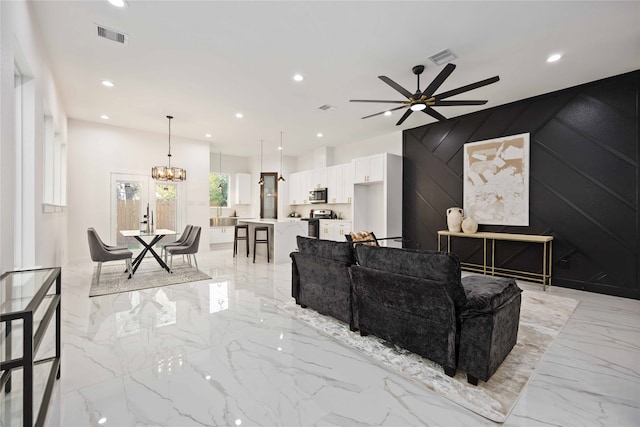 living room featuring ceiling fan with notable chandelier and wood walls