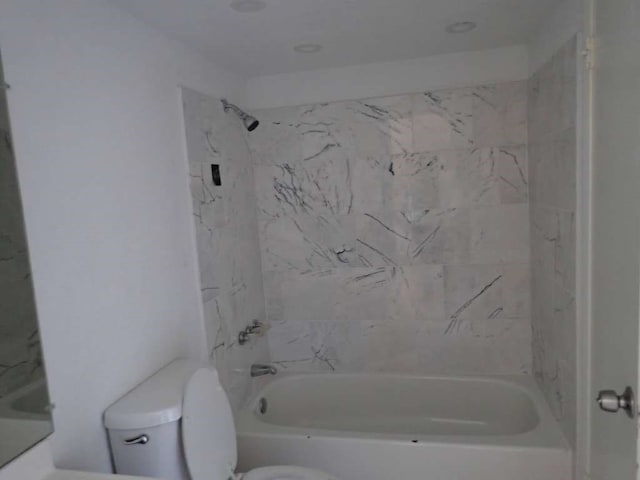 bathroom featuring tiled shower / bath and toilet