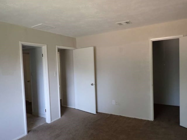 unfurnished bedroom featuring dark colored carpet, a spacious closet, and a closet