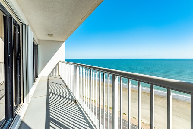 balcony with a water view and a view of the beach