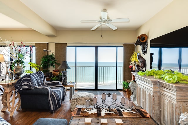 living room featuring dark wood-type flooring, a water view, and ceiling fan