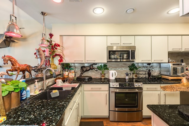 kitchen with decorative backsplash, hanging light fixtures, stainless steel appliances, dark stone counters, and sink