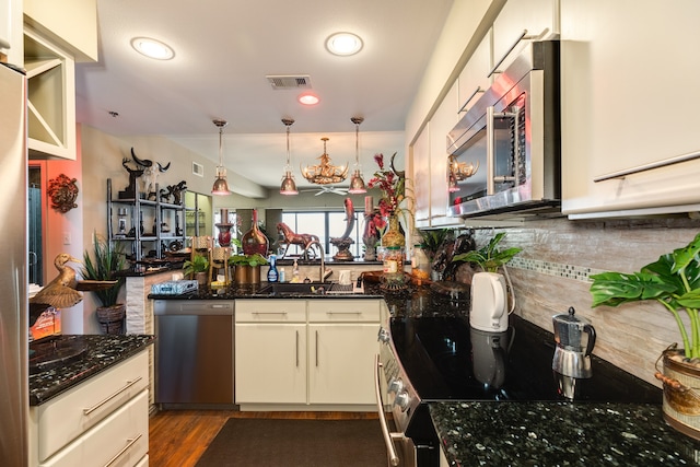 kitchen featuring decorative light fixtures, stainless steel appliances, sink, and dark stone counters