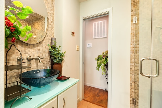 bathroom with vanity, hardwood / wood-style floors, backsplash, and an enclosed shower