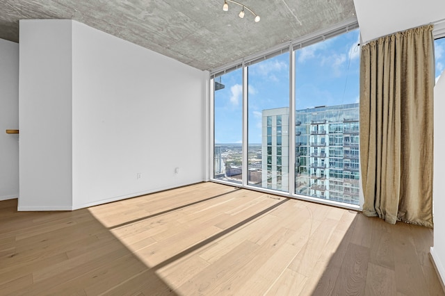 unfurnished room featuring hardwood / wood-style flooring and a wall of windows