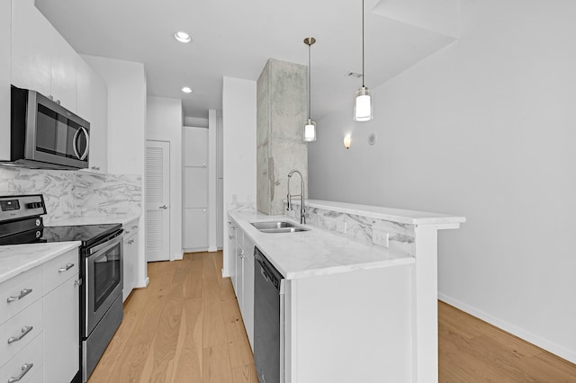 kitchen with pendant lighting, sink, appliances with stainless steel finishes, tasteful backsplash, and white cabinetry