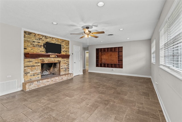 unfurnished living room with ceiling fan and a brick fireplace