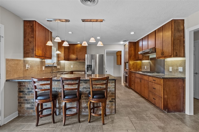 kitchen featuring sink, appliances with stainless steel finishes, tasteful backsplash, a breakfast bar area, and decorative light fixtures