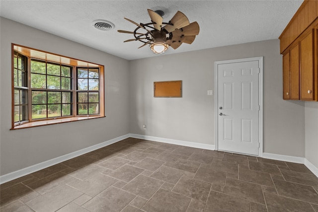 empty room featuring ceiling fan and a textured ceiling