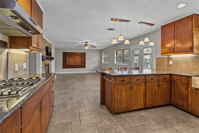 kitchen with tasteful backsplash, extractor fan, hanging light fixtures, stainless steel gas stovetop, and ceiling fan