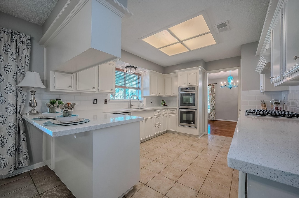 kitchen with sink, stainless steel appliances, backsplash, kitchen peninsula, and white cabinets