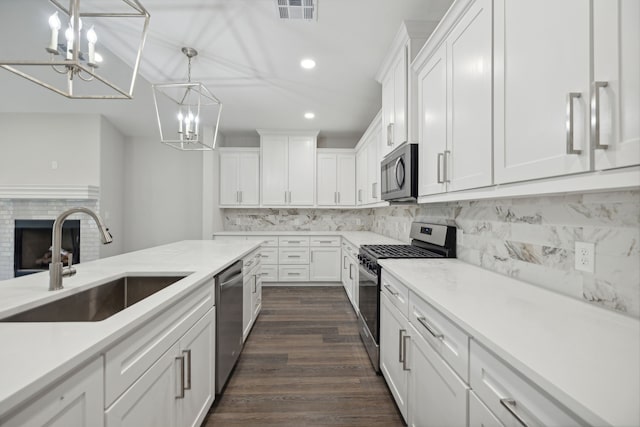 kitchen featuring visible vents, white cabinetry, a chandelier, a sink, and stainless steel appliances