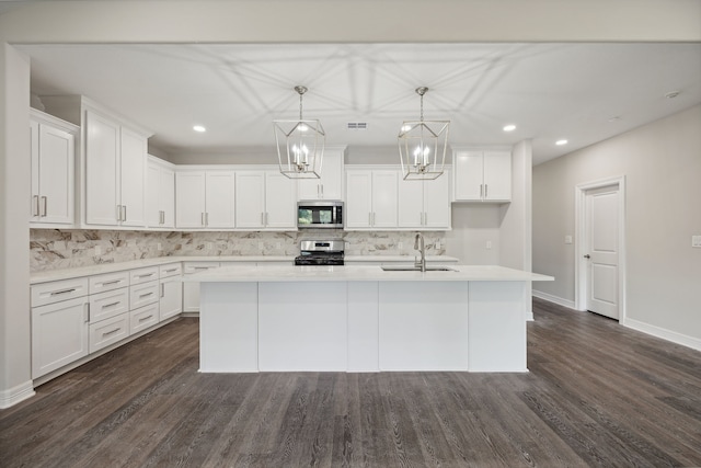 kitchen with a sink, decorative backsplash, a kitchen island with sink, and stainless steel appliances