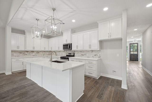 kitchen featuring a kitchen island with sink, dark wood-type flooring, white cabinets, a sink, and appliances with stainless steel finishes
