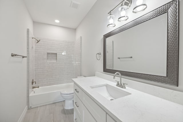 bathroom featuring vanity, visible vents, wood finished floors, toilet, and bathtub / shower combination