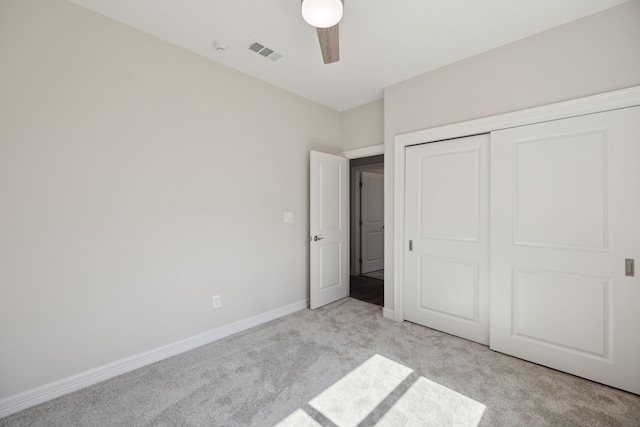 unfurnished bedroom with visible vents, a closet, light carpet, baseboards, and ceiling fan