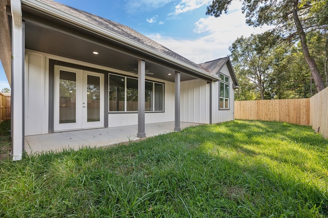 back of property with a patio, a fenced backyard, french doors, a shingled roof, and a lawn