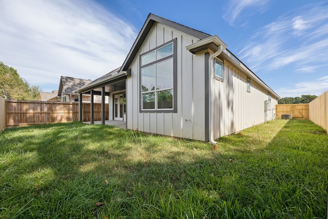rear view of house featuring board and batten siding, a yard, and a fenced backyard