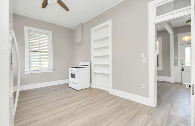 kitchen with white range, light wood-type flooring, a wealth of natural light, and ceiling fan