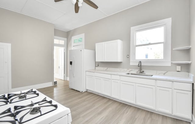 kitchen with white appliances, sink, light wood-type flooring, and white cabinets