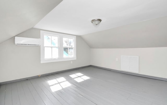 bonus room featuring light hardwood / wood-style flooring, a wall unit AC, and lofted ceiling