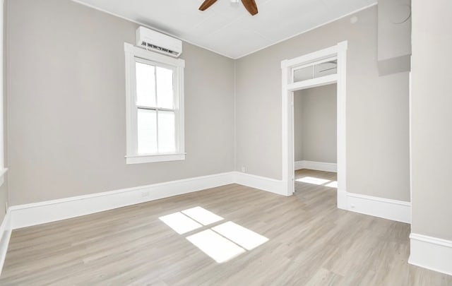 spare room with light hardwood / wood-style flooring, a wall unit AC, and ceiling fan