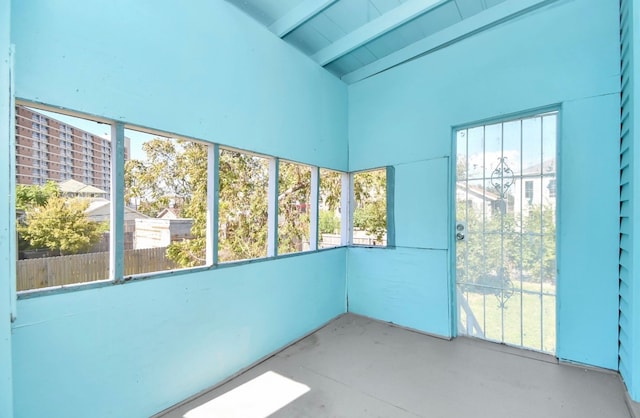 unfurnished sunroom with vaulted ceiling with beams