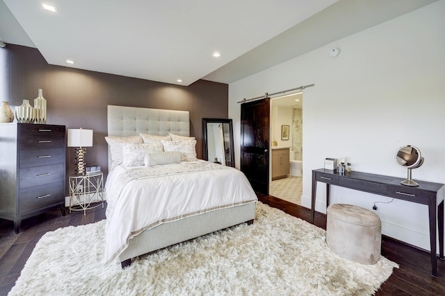 bedroom featuring recessed lighting, wood finished floors, ensuite bath, a barn door, and baseboards