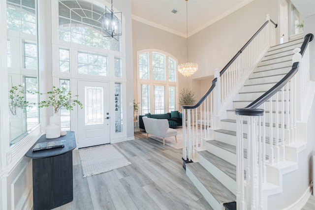 entrance foyer featuring ornamental molding, a chandelier, wood-type flooring, and a high ceiling