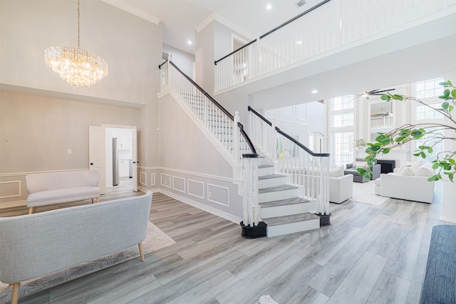 stairs with a towering ceiling, hardwood / wood-style floors, and a chandelier