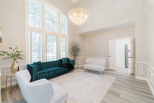 living room with light hardwood / wood-style floors, a towering ceiling, and a chandelier