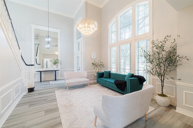 living room featuring a towering ceiling, crown molding, hardwood / wood-style flooring, and an inviting chandelier