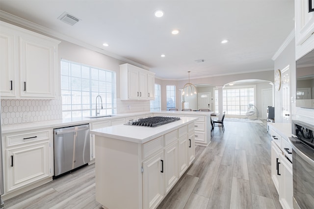 kitchen featuring a kitchen island, light hardwood / wood-style flooring, sink, appliances with stainless steel finishes, and tasteful backsplash