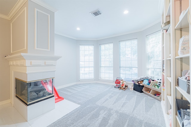 recreation room with a multi sided fireplace, light colored carpet, and crown molding