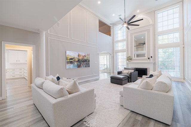 living room with light hardwood / wood-style floors, a high ceiling, and ceiling fan