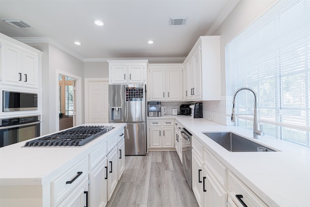 kitchen with appliances with stainless steel finishes, crown molding, sink, and a wealth of natural light