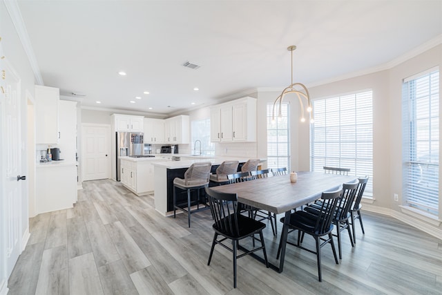 dining room featuring sink, crown molding, and light hardwood / wood-style flooring