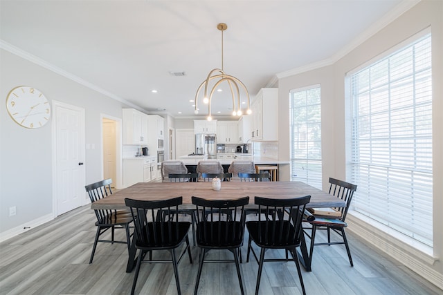 dining space featuring ornamental molding, light hardwood / wood-style flooring, and an inviting chandelier