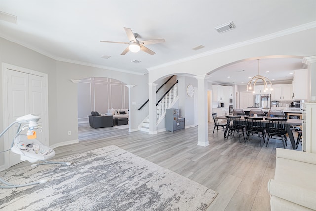 living room with ornamental molding, ornate columns, ceiling fan with notable chandelier, and light hardwood / wood-style floors