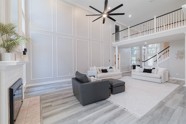 living room featuring light hardwood / wood-style floors, a towering ceiling, and ceiling fan