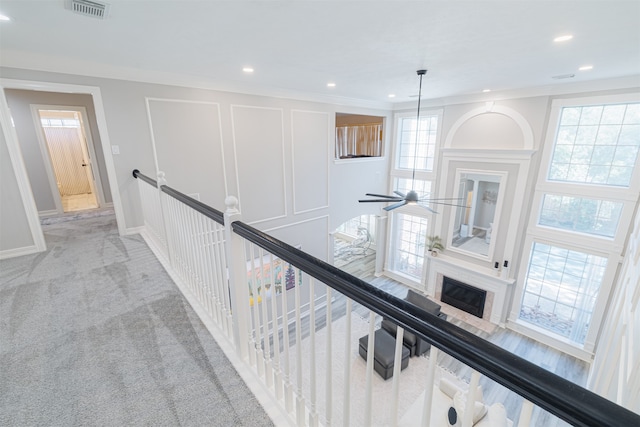 corridor featuring ornamental molding, a wealth of natural light, and light colored carpet