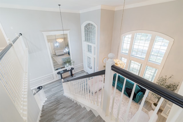 stairs featuring crown molding, hardwood / wood-style flooring, and a chandelier