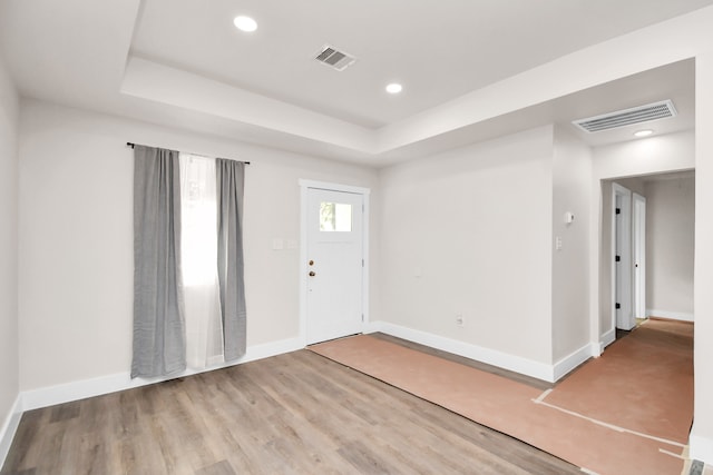 entrance foyer with hardwood / wood-style flooring and a raised ceiling