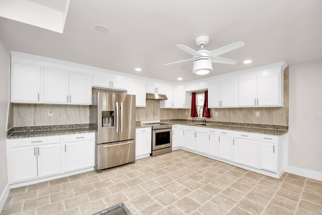 kitchen featuring appliances with stainless steel finishes, sink, dark stone counters, and white cabinets