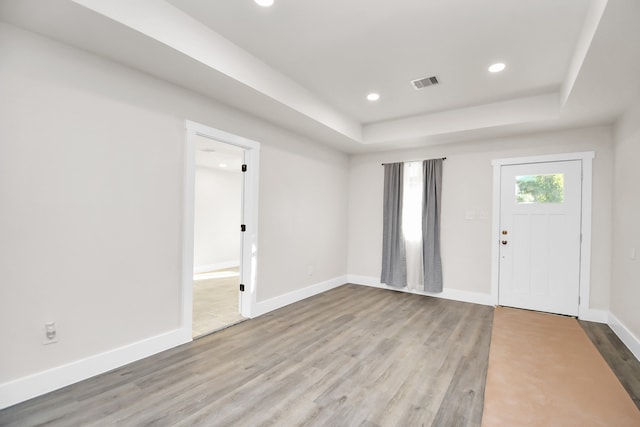 entryway with a tray ceiling and light wood-type flooring