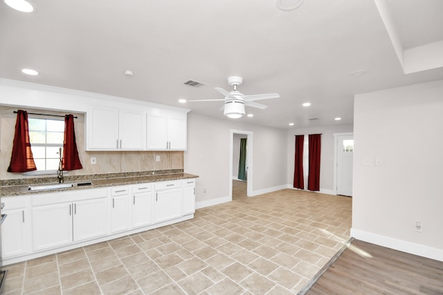 kitchen with white cabinetry, sink, and ceiling fan