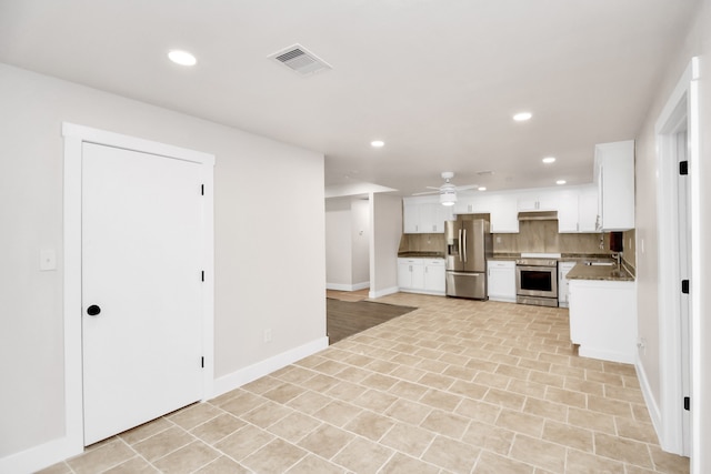 kitchen featuring backsplash, white cabinetry, ceiling fan, stainless steel appliances, and dark stone countertops