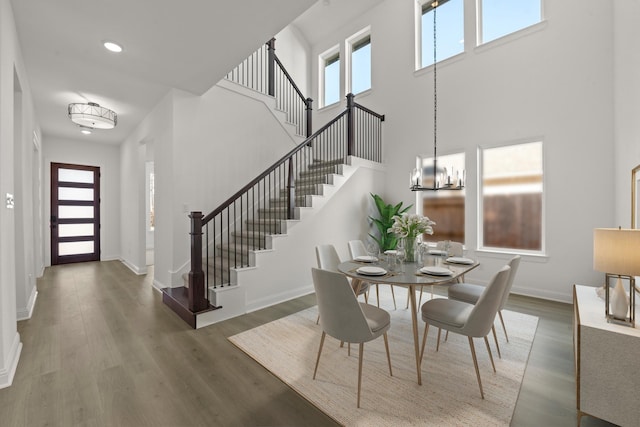 dining space featuring a towering ceiling, dark hardwood / wood-style floors, and a notable chandelier